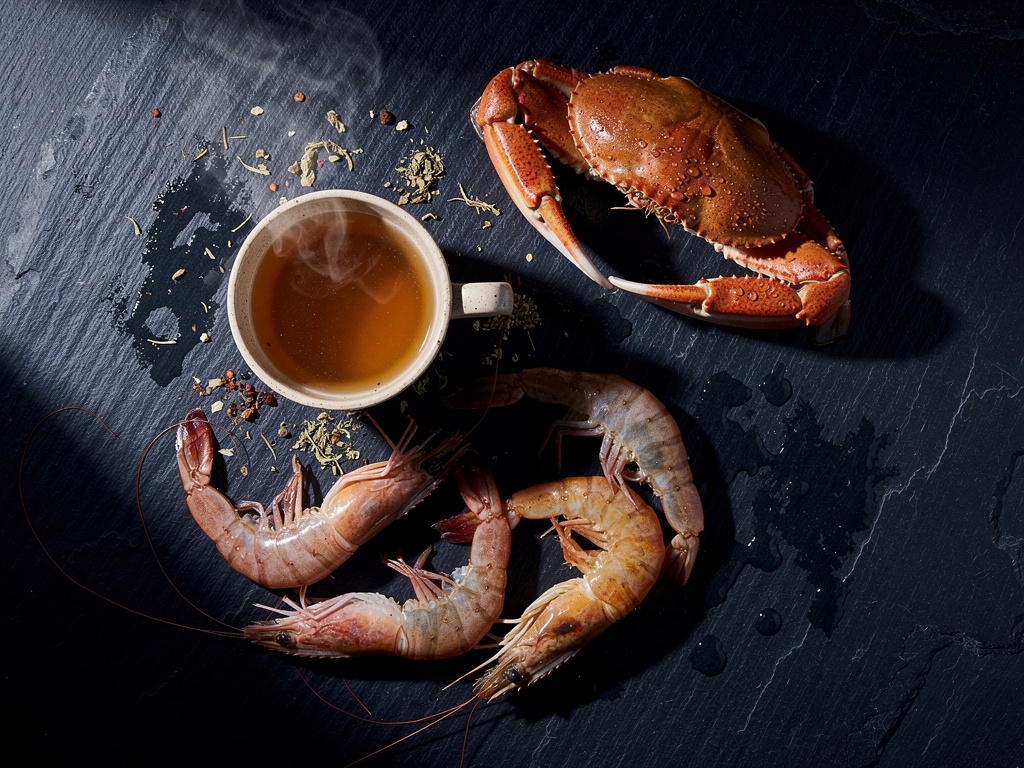 Mariscos frescos y caldos naturales sobre tabla de madera con iluminación cálida que evoca fuentes naturales de glucosamina